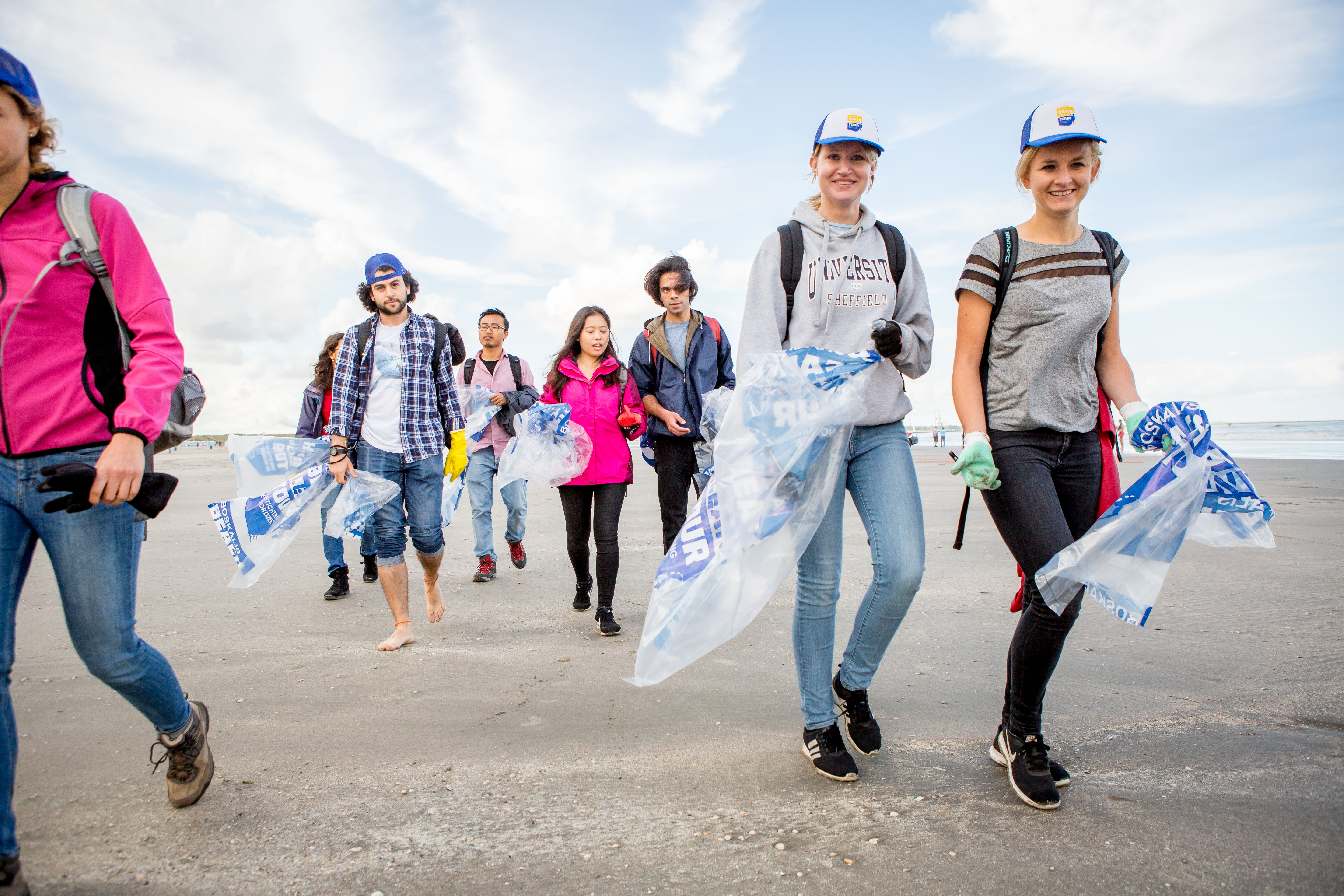 mensen lopen op strand met vuilniszakken
