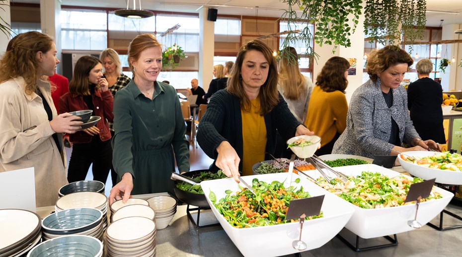 mensen scheppen salade op in een kantine